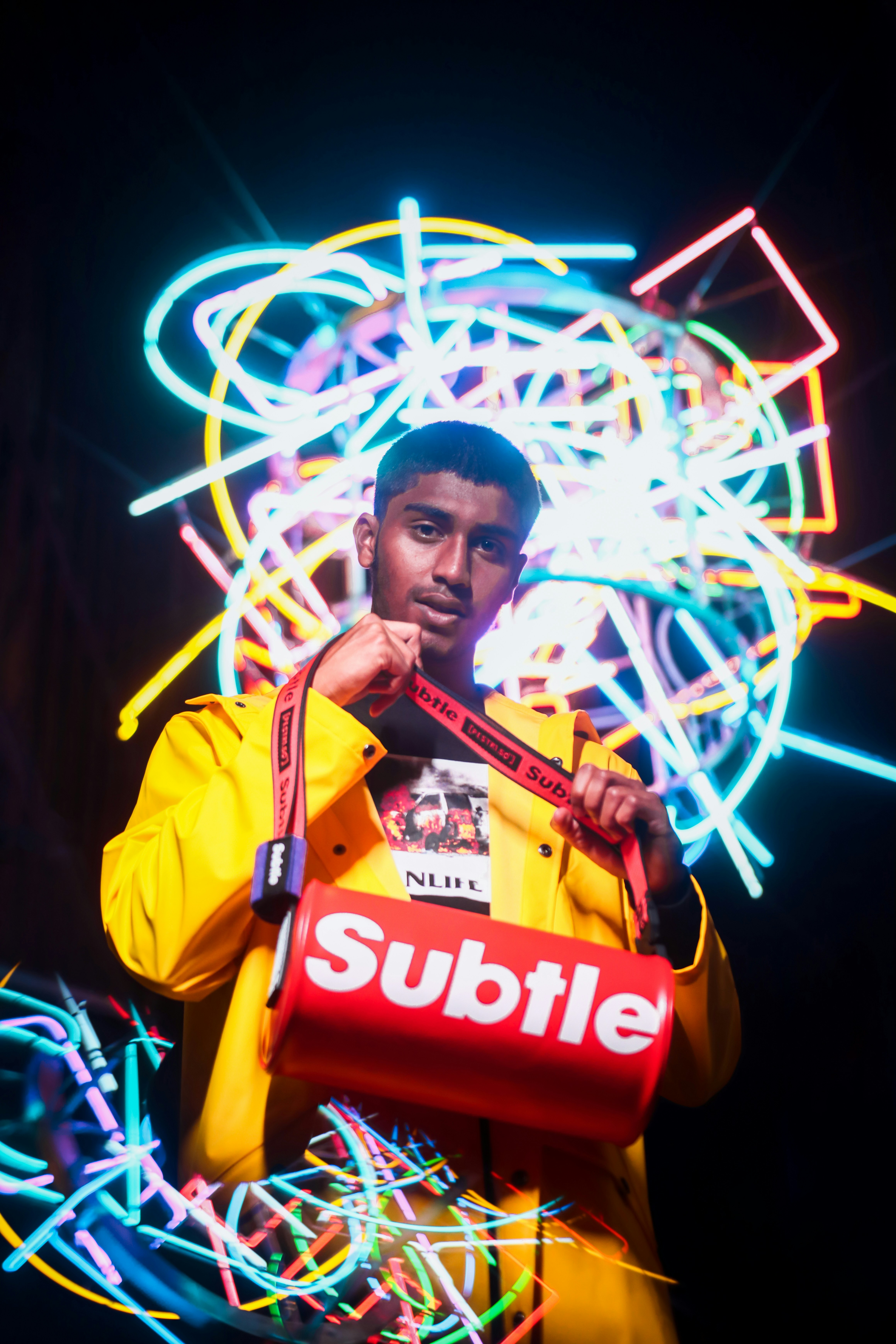 Seorang pria berjaket kuning memegang tas merah
