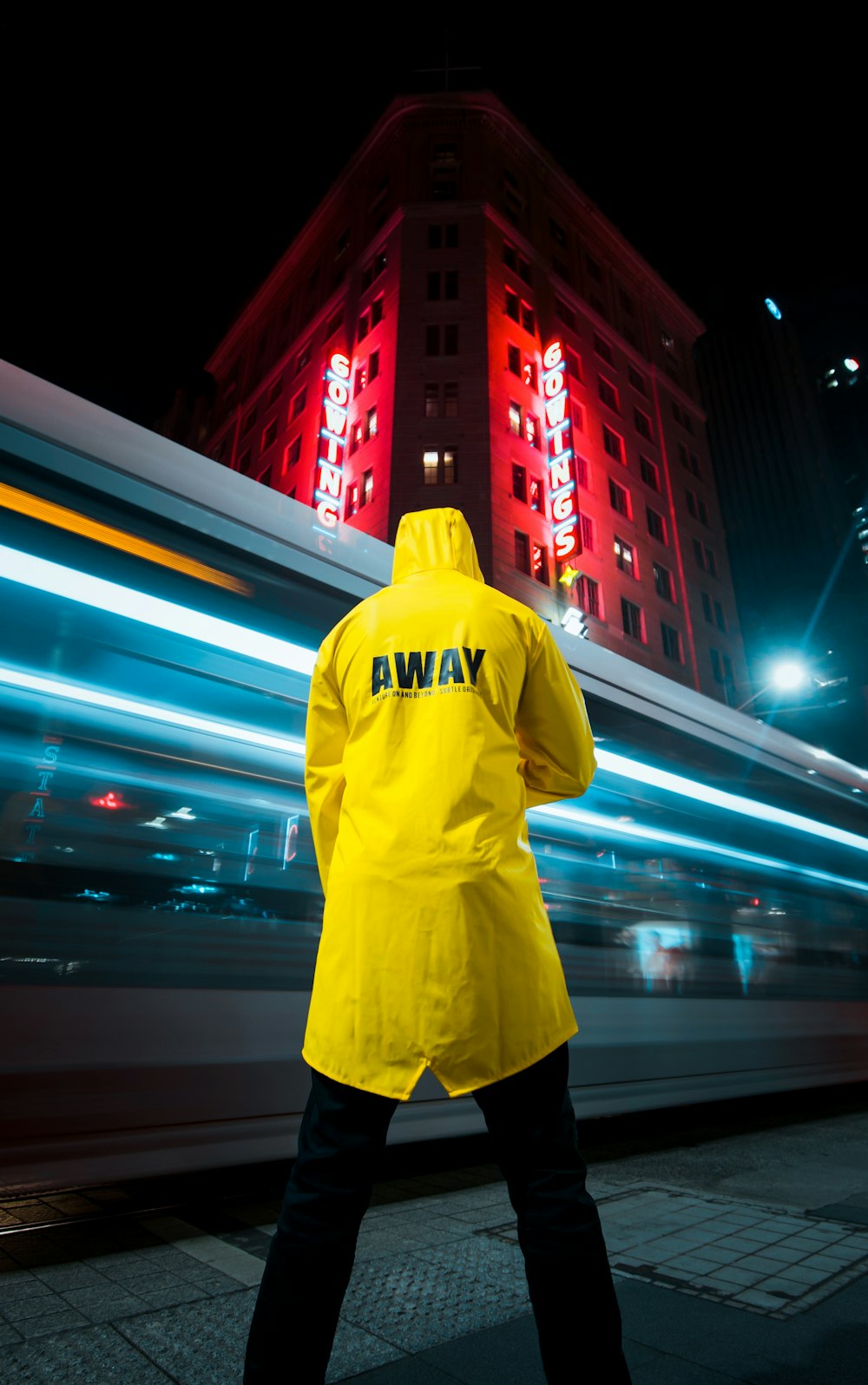 Mann in gelbem Kapuzenpullover steht nachts auf der Straße