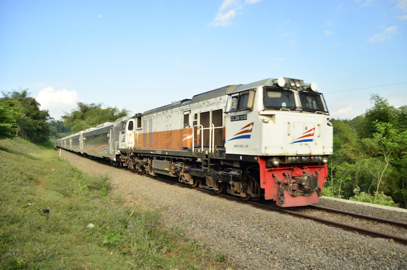 Kereta merah abu-abu di rel, panduan langkah sewa kereta wisata rombongan