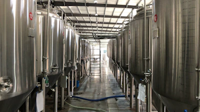 Industrial stainless steel components lined up in a bright manufacturing facility.