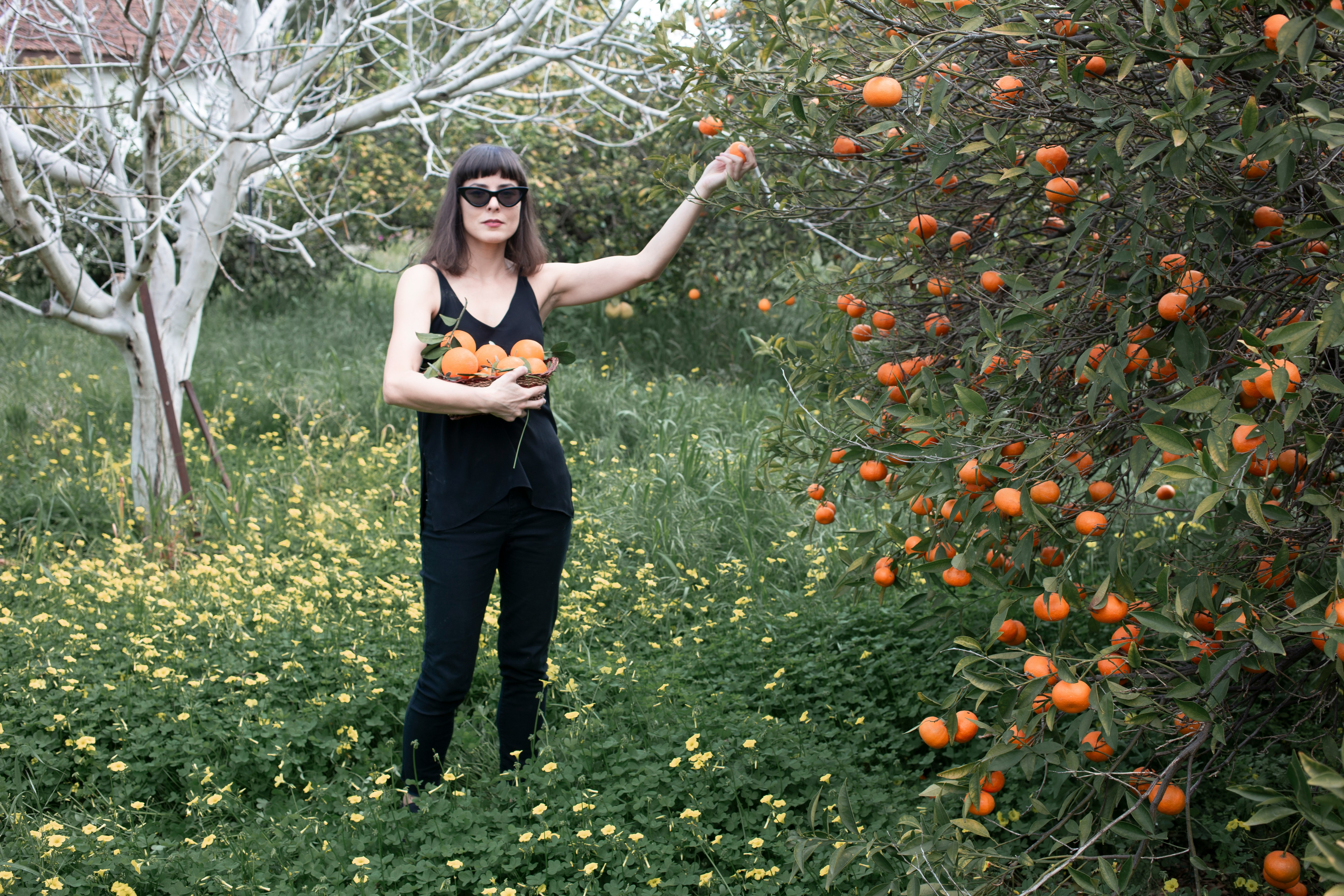 woman in black tank top and black pants standing on green grass field during daytime