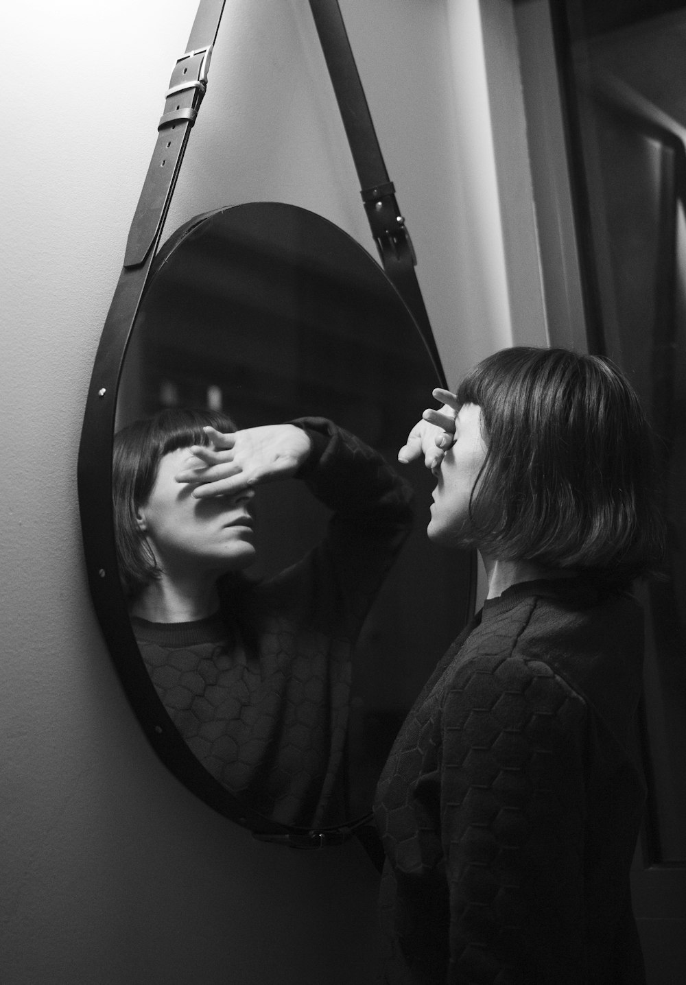 鏡の前に立つ黒い長袖シャツを着た女性