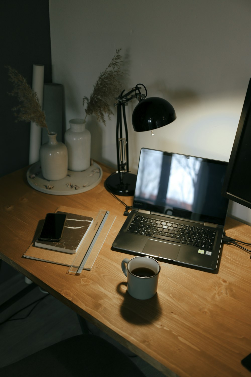 black laptop computer beside white ceramic mug on brown wooden table