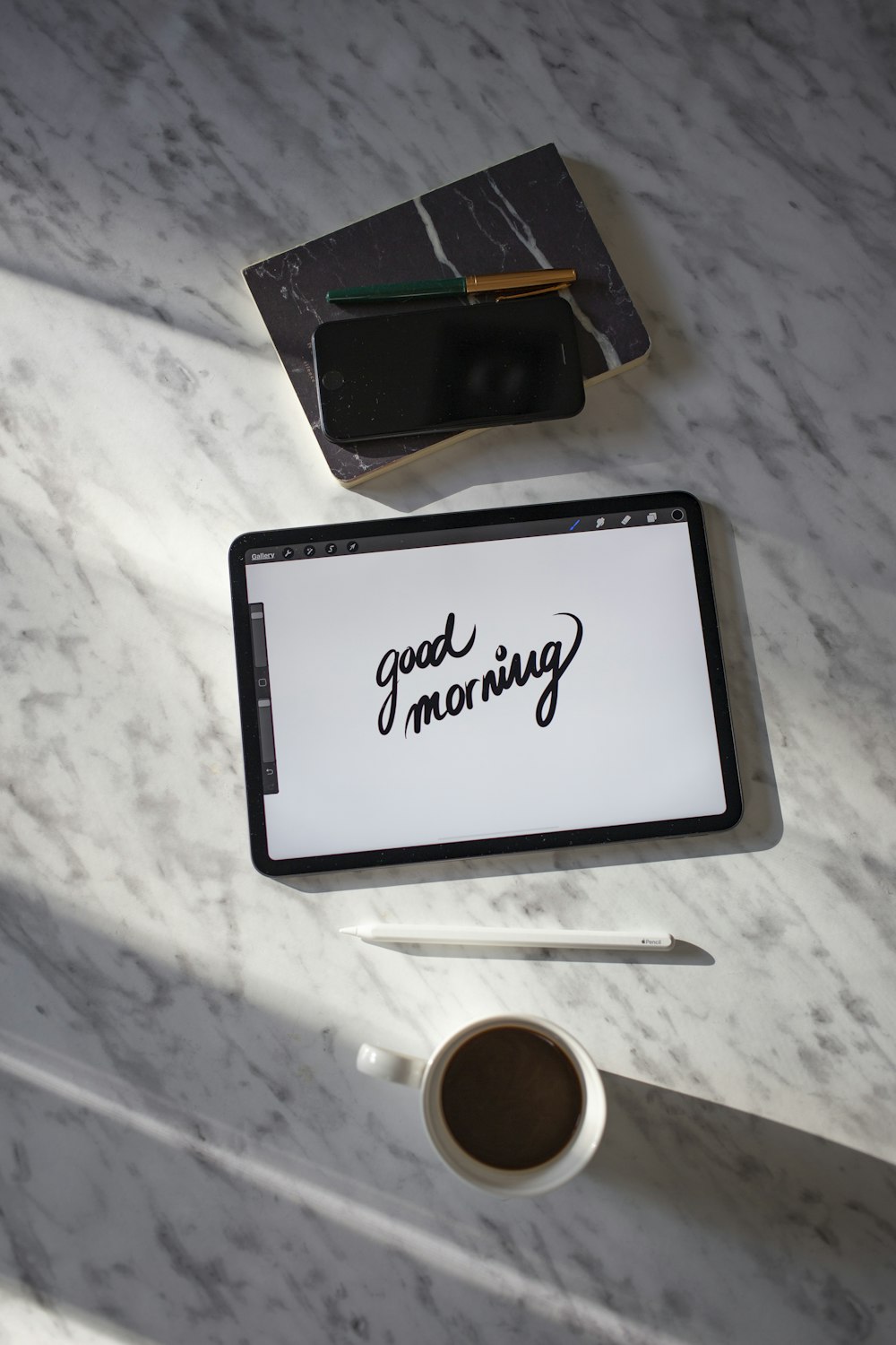 black tablet computer beside white ceramic mug on white table