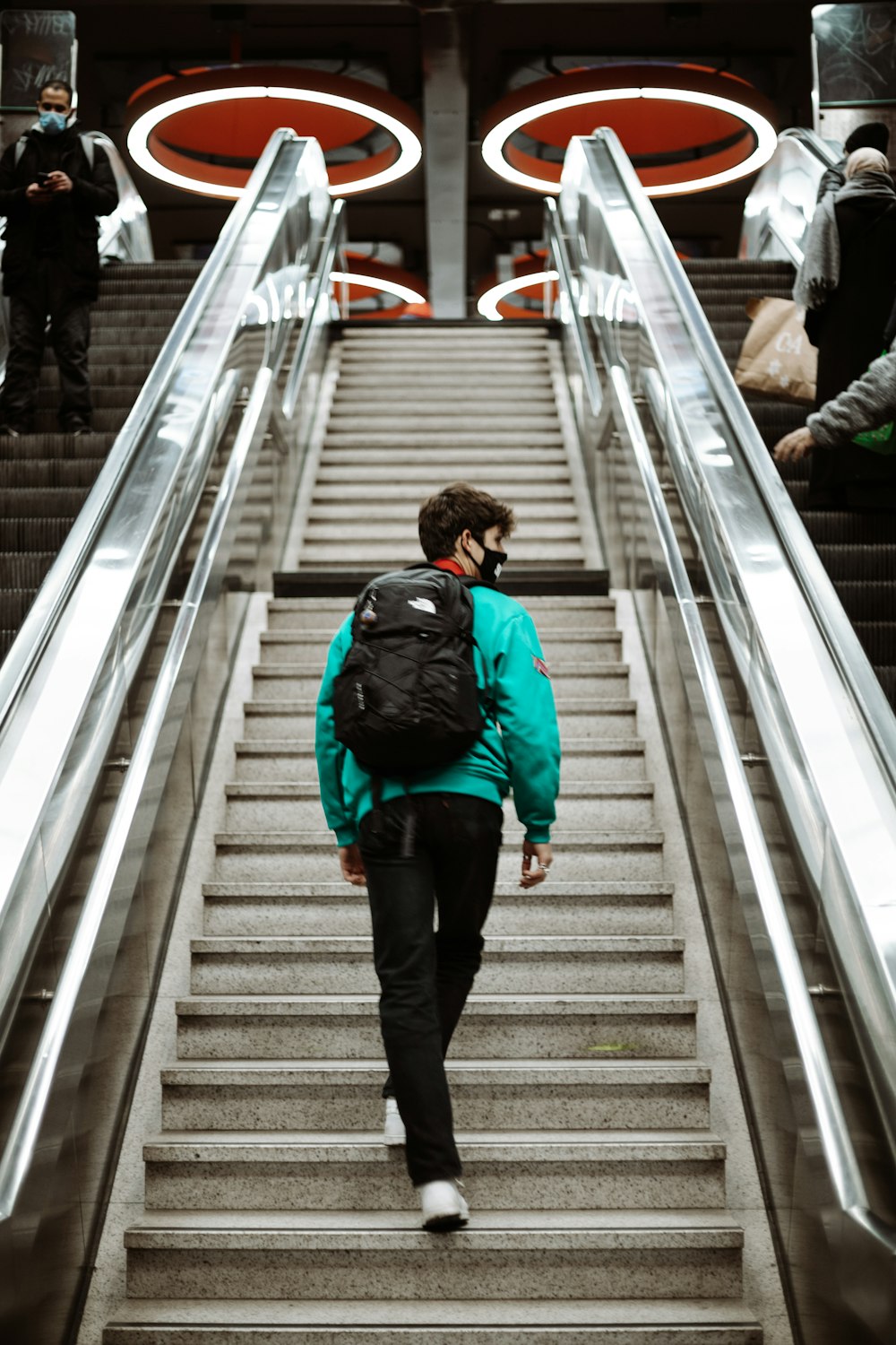 man in red jacket and black pants walking down the stairs