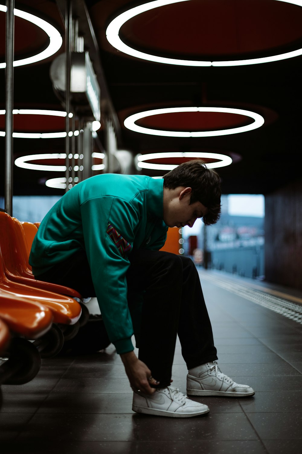 man in green long sleeve shirt and black pants standing on black and red arcade game