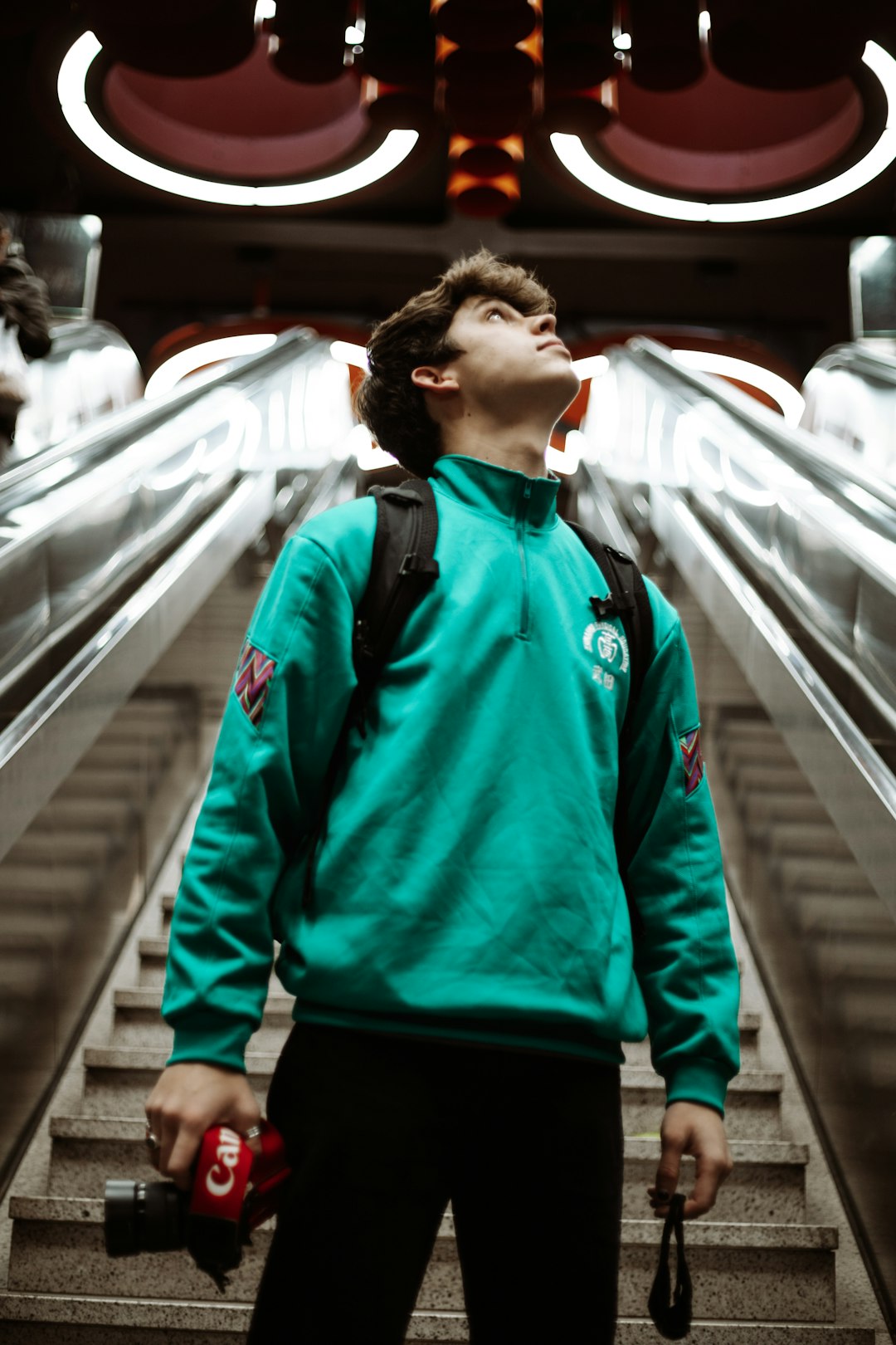 man in blue and black zip up jacket walking on the train station