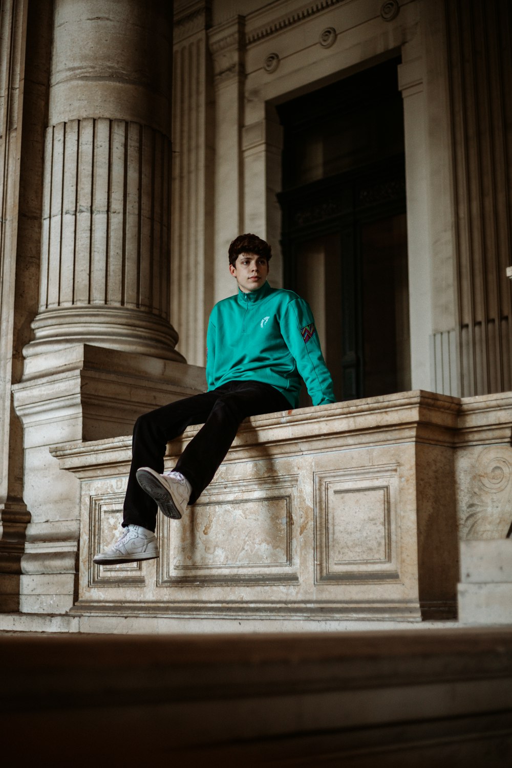 man in red dress shirt and black pants sitting on concrete stairs