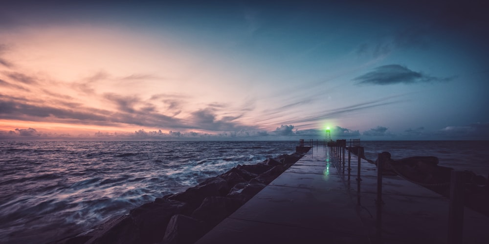 silhouette of dock on sea during sunset