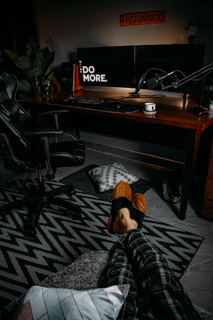 A cozy workspace with a gaming setup, microphone, and horror game posters on the wall.