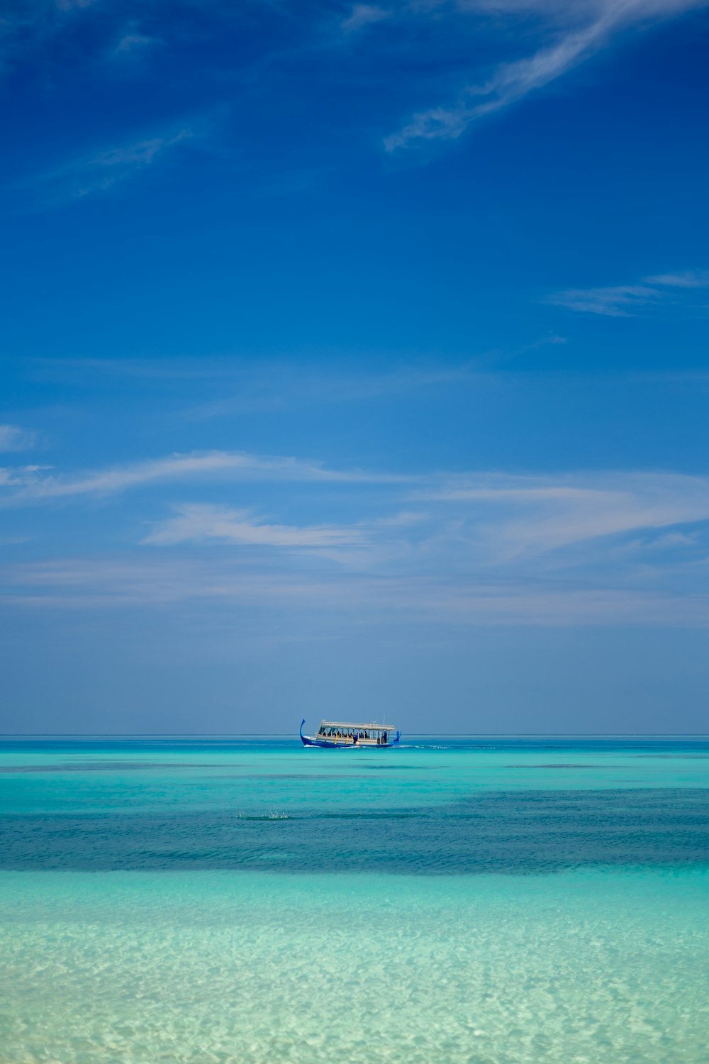 white and black boat on sea under blue sky during daytime