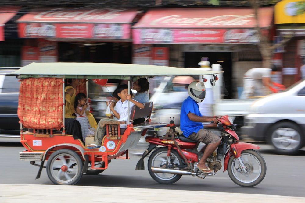 2 men riding red and black motorcycle on road during daytime