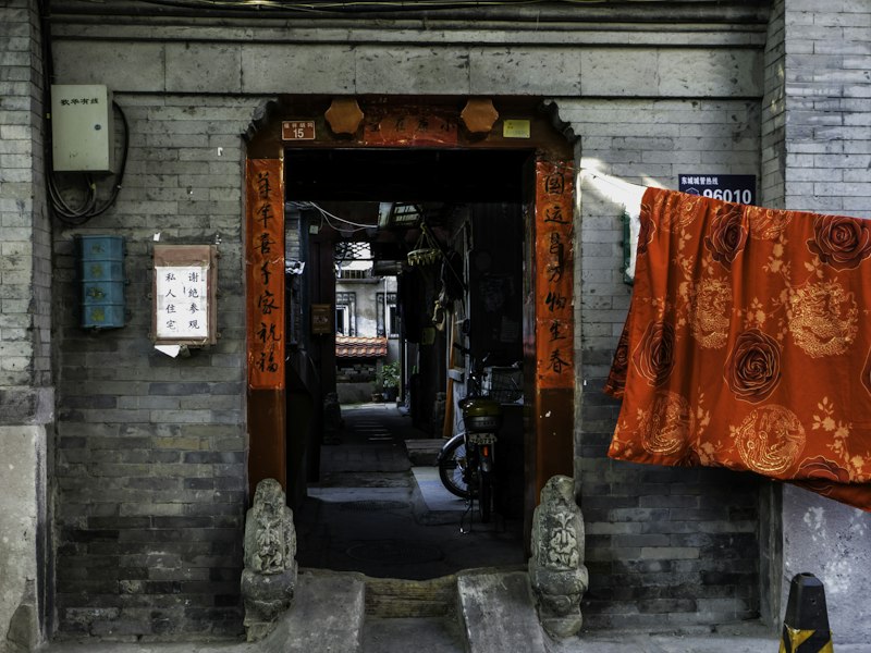 Beijing hutong food alley with traditional courtyard restaurant entrance and steaming dumplings
