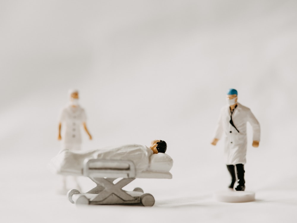 man in white coat and black pants standing beside white wooden picnic table