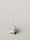 A miniature figurine of a nurse stands beside a hospital bed with a patient lying under a white blanket. The scene is minimalist with a pale background, emphasizing the medical figures.