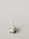 A miniature figurine of a nurse stands beside a hospital bed with a patient lying under a white blanket. The scene is minimalist with a pale background, emphasizing the medical figures.