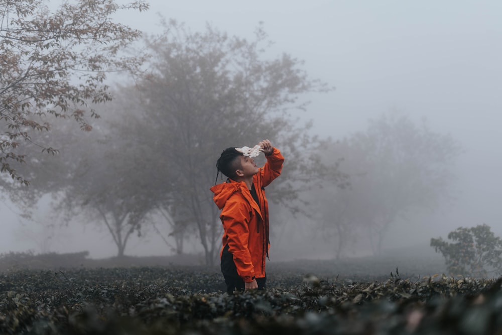 man in orange hoodie standing on black rock