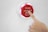 A hand is pressing a red button that has the text 'Press when full' and an envelope icon on it. The button is mounted on a white surface.