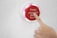 A hand is pressing a red button that has the text 'Press when full' and an envelope icon on it. The button is mounted on a white surface.