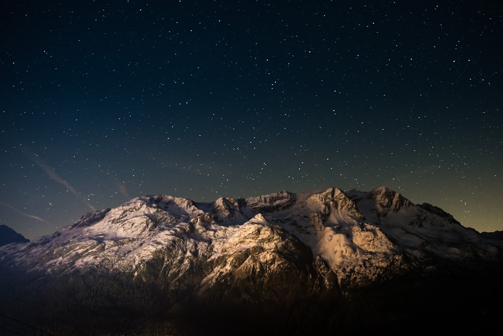 montagna coperta di neve sotto il cielo blu durante la notte