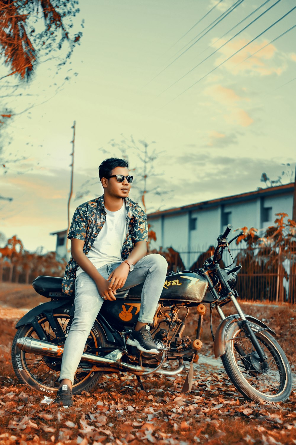 woman in white and black floral shirt and blue denim jeans sitting on motorcycle