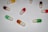 Several capsules are arranged on a white surface. These capsules come in various colors including red, green, yellow, and orange. Each capsule has a happy face drawn on it, giving them a friendly and playful appearance.