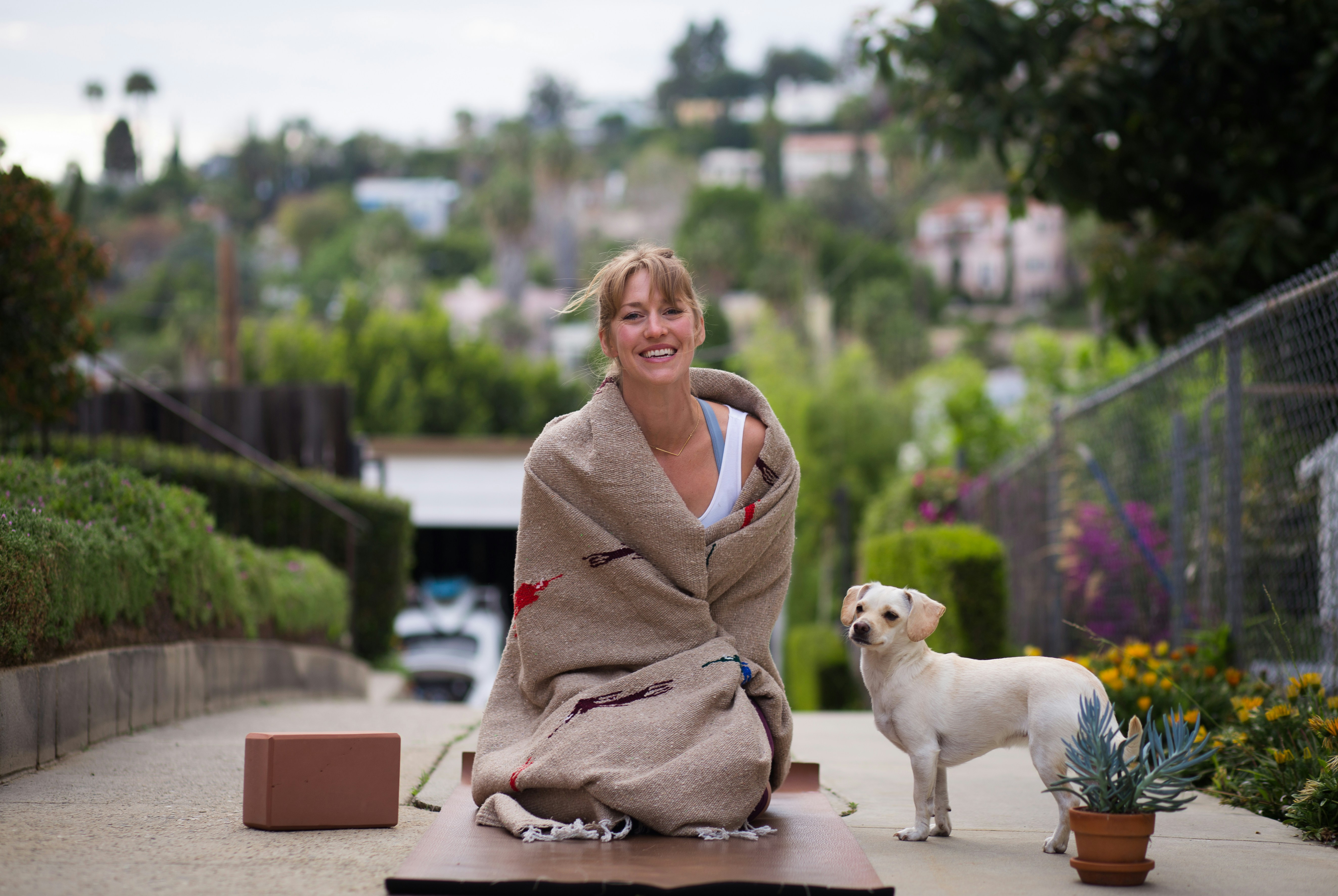 woman in brown robe sitting beside white short coated dog during daytime
