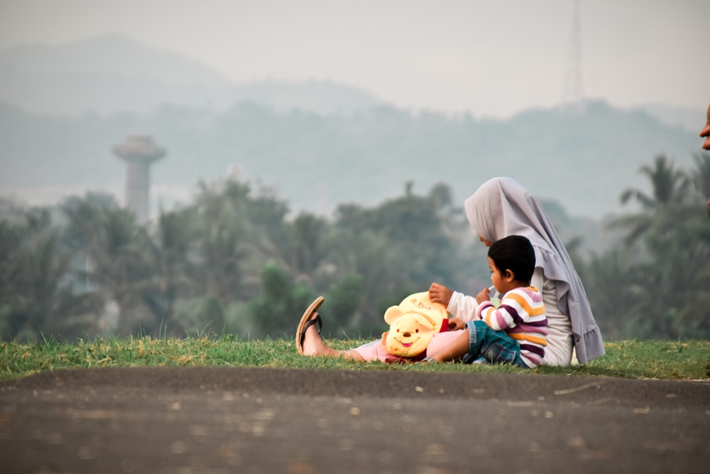 2 children sitting on ground during daytime