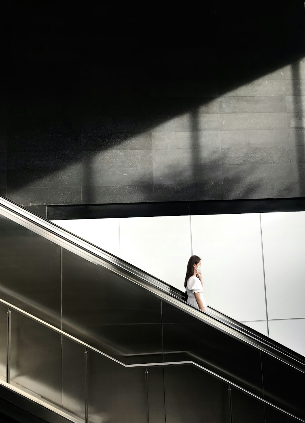 woman in white shirt standing on escalator