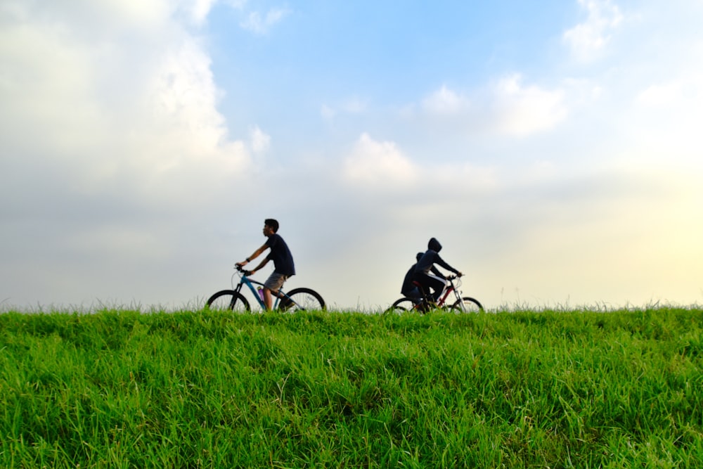 man in black shirt riding bicycle on green grass field during daytime