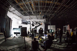 A film crew working on a large soundstage with lighting equipment and cameras