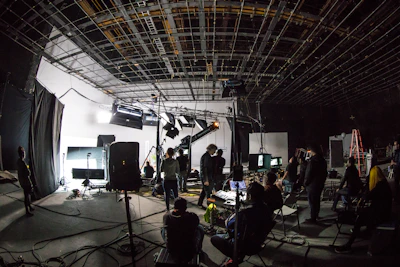 A film crew working on a large soundstage with lighting equipment and cameras