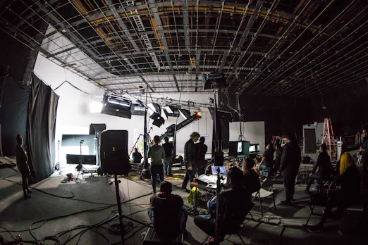 A film crew working on a large soundstage with lighting equipment and cameras
