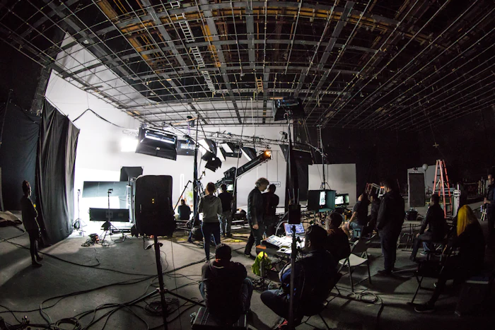 A film crew working on a large soundstage with lighting equipment and cameras