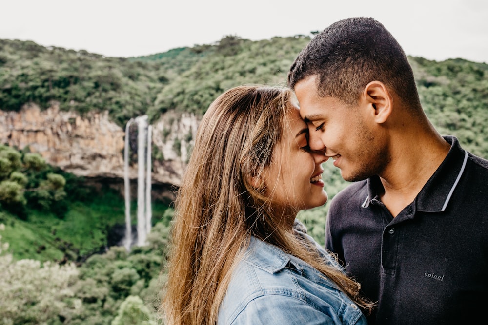 man and woman kissing near green trees during daytime