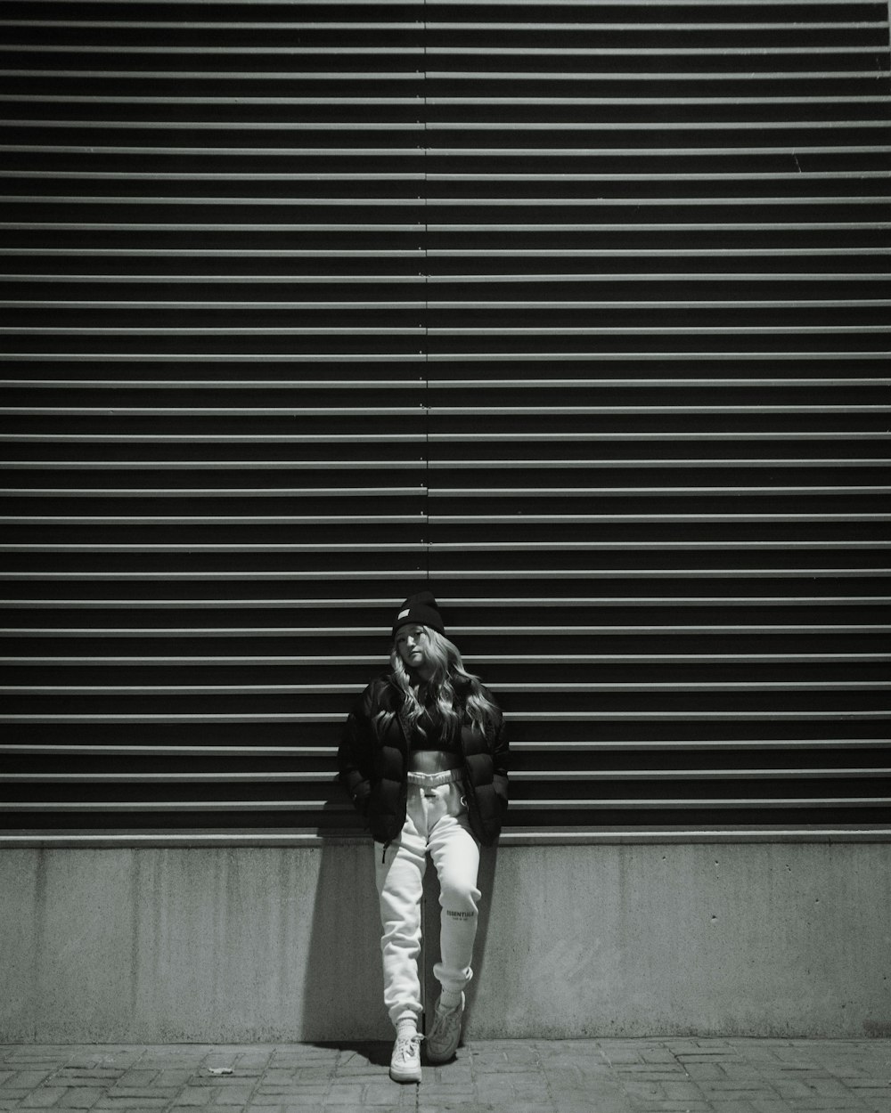 woman in black jacket and gray pants standing in front of roll up door