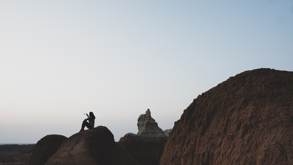 silhouette of man standing on rock formation during daytime