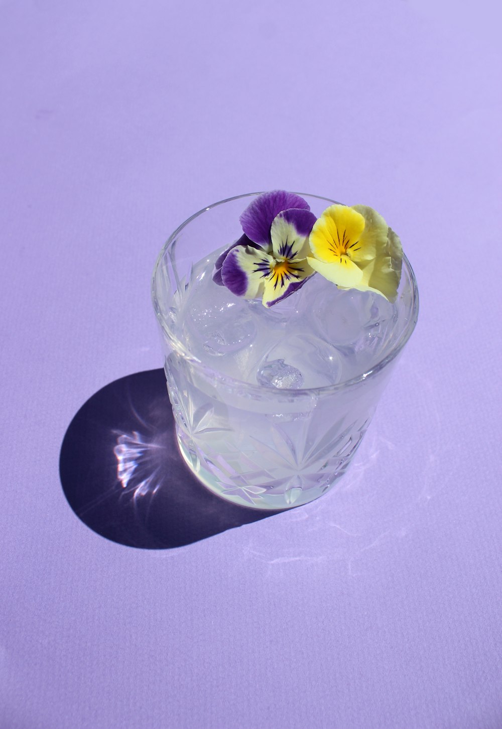 clear drinking glass with water and yellow flower