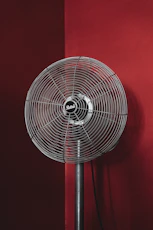 black stand fan turned on in red room