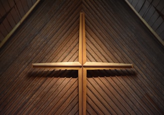 brown wooden cross on brown wooden wall