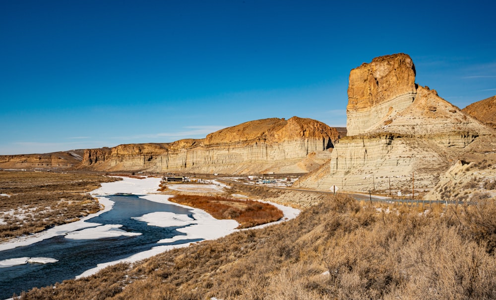 brown rocky mountain beside blue sea under blue sky during daytime