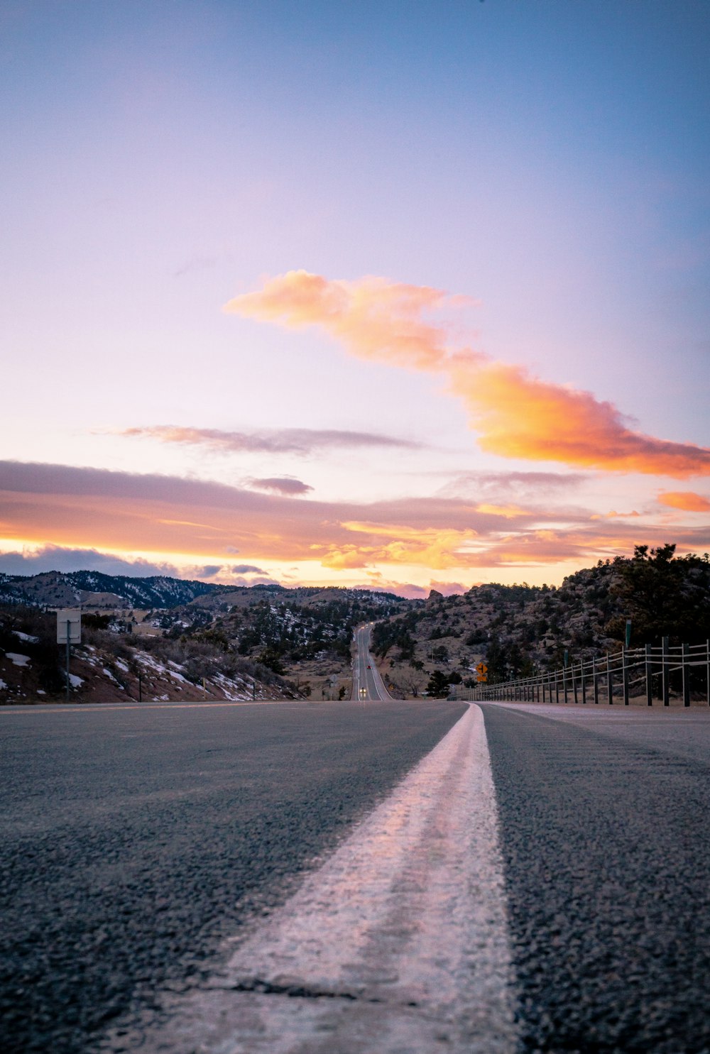 gray concrete road between trees and houses under cloudy sky during daytime