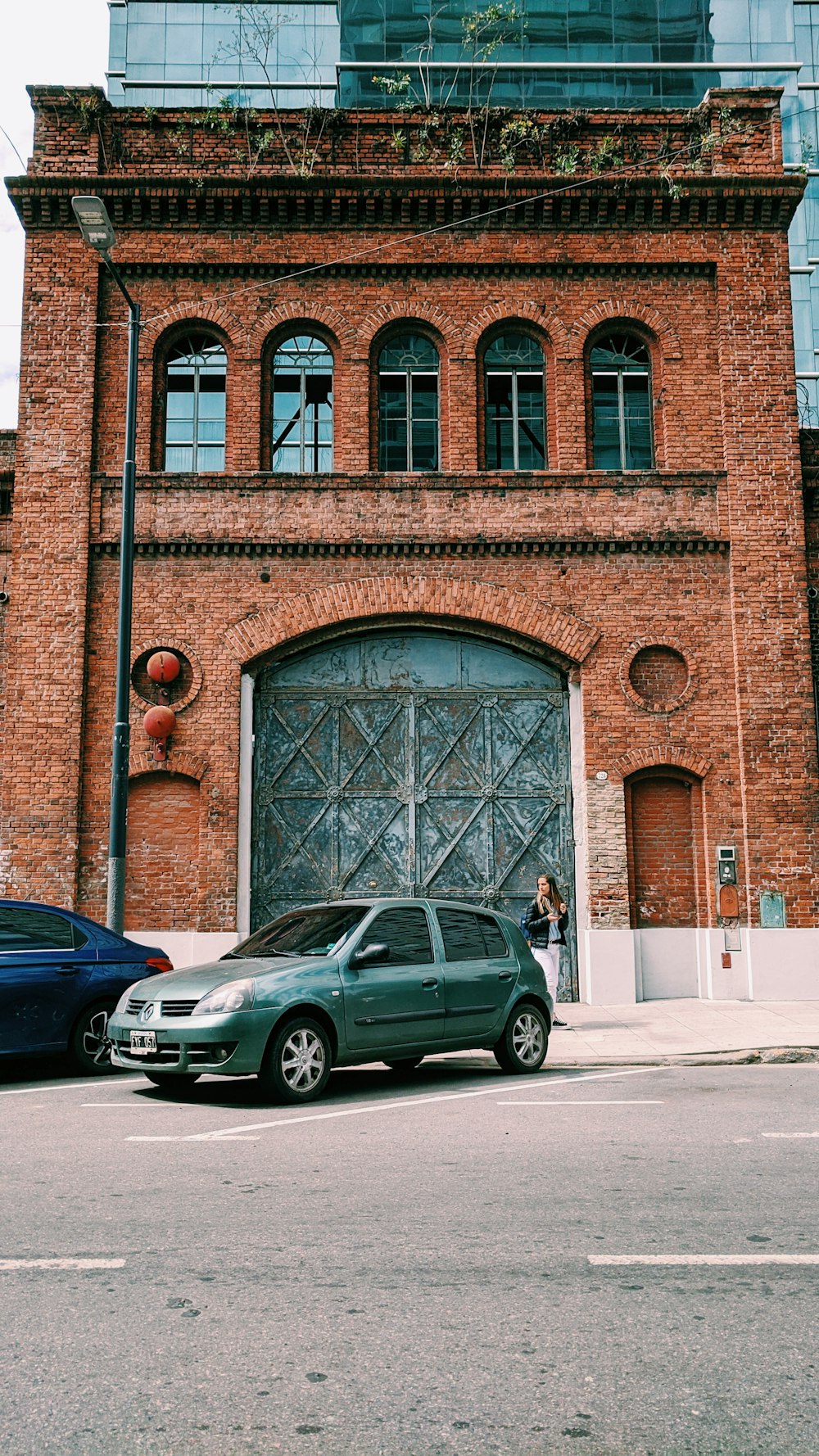 black sedan parked beside brown concrete building during daytime