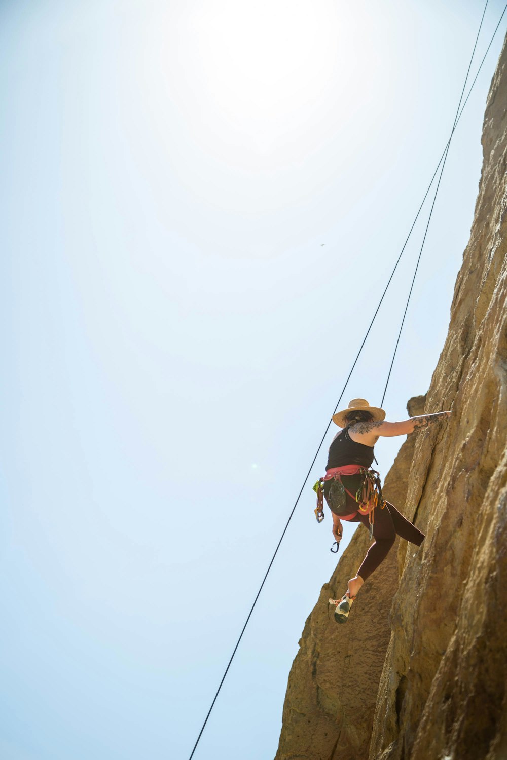 man in red shirt and brown shorts climbing on brown rock during daytime