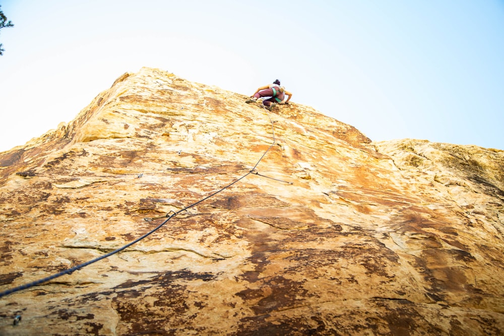 man climbing on brown rocky mountain during daytime