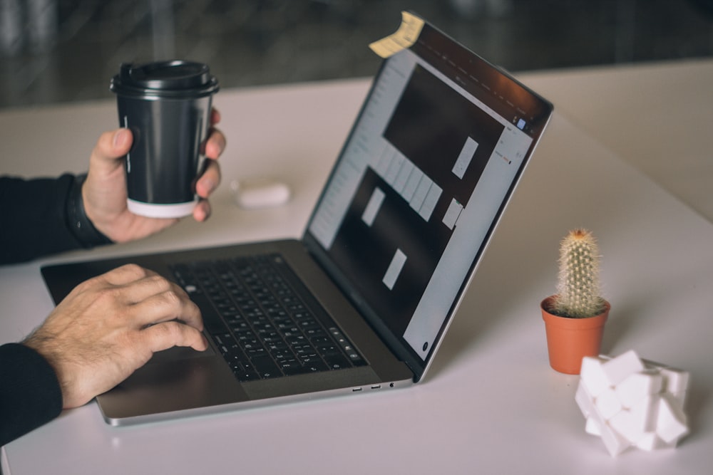 person using macbook pro on white table