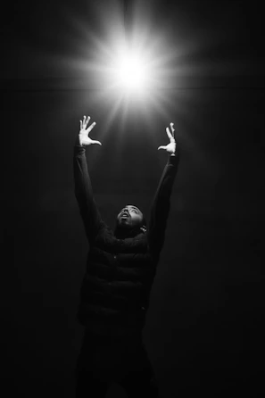 grayscale photo of man raising his hands
