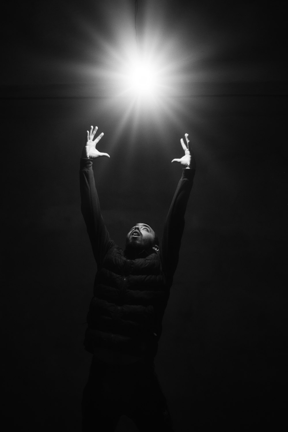 grayscale photo of man raising his hands