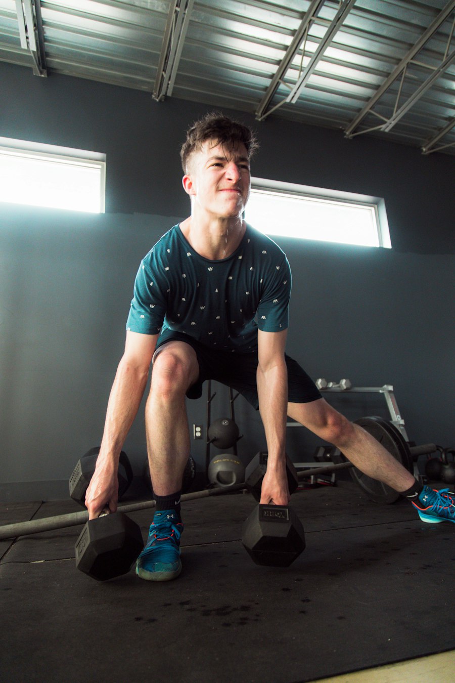 Client pulling a heavy dumbbell deadlift during a strength and conditioning session