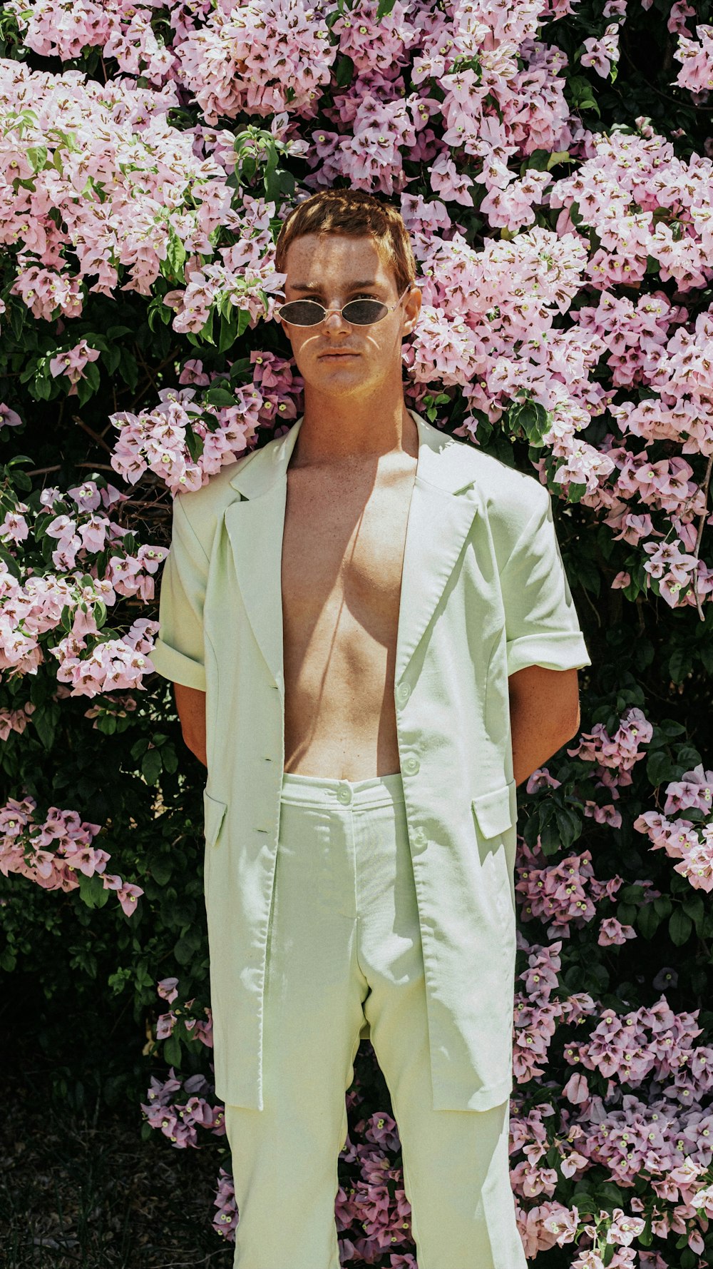 woman in white button up shirt standing beside purple flowers